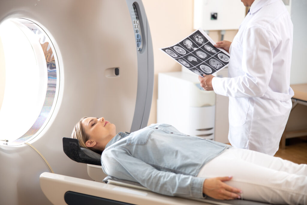 Young lady lying on CT scanner table after tomography test in hospital