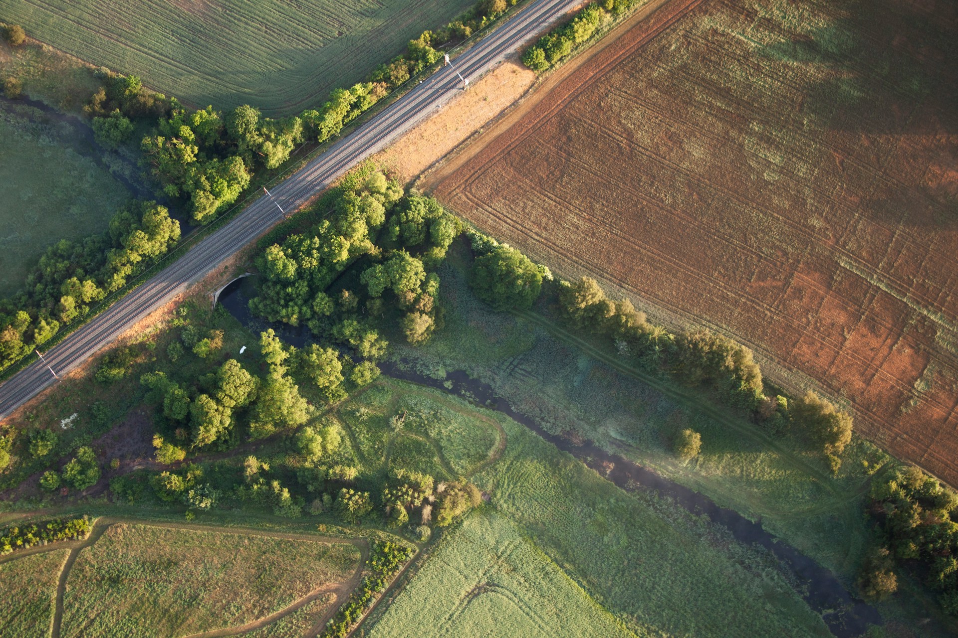 Aerial view of a road cutting through a field, seen from above.