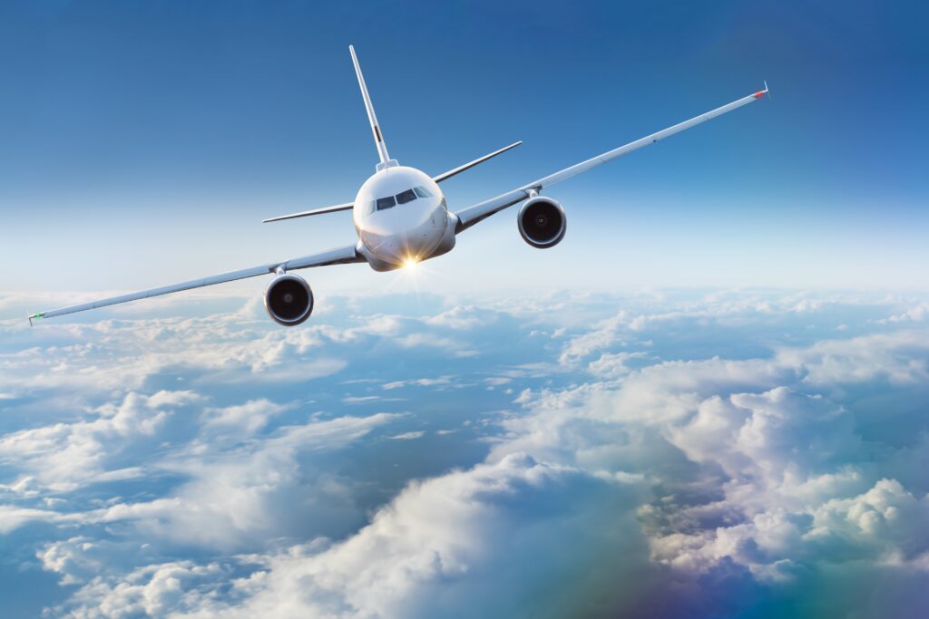 Plane flying above clouds, turning towards the upper left side of the image